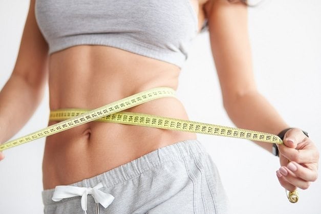 Slim girl with centimeter on white