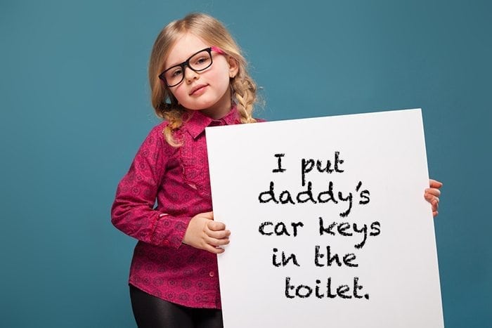 Adorable little girl in pink shirt, black trousers and glasses holds empty poster
